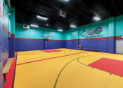 Thumbnail 16 of 20 - a basketball court in a gym with a blue wall and a red and yellow floor