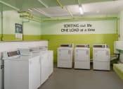 Thumbnail 17 of 20 - a laundry room with four washing machines and a sign on the wall