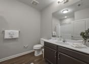 Thumbnail 37 of 38 - A white toilet sits in a bathroom with brown cabinets.