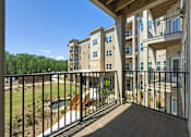 Thumbnail 38 of 38 - A balcony with a black railing and a view of a building and trees.