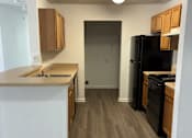 Thumbnail 10 of 16 - A kitchen with a black refrigerator and wooden cabinets.