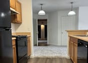 Thumbnail 12 of 16 - A kitchen with black appliances and wooden cabinets.