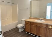Thumbnail 14 of 16 - A white toilet sits in a bathroom next to a sink and a bathtub.