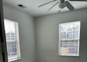 Thumbnail 8 of 16 - A room with a ceiling fan and two windows.