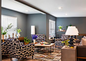 Thumbnail 5 of 10 - A living room with a patterned sofa, a coffee table, and a lamp.
