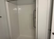 Thumbnail 5 of 15 - a shower with a shower handle in a small bathroom
