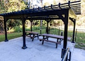 Thumbnail 4 of 10 - A black pergola with a picnic table underneath it.