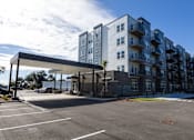 Thumbnail 5 of 10 - A large parking lot in front of a modern apartment building.