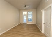 Thumbnail 9 of 10 - A room with a ceiling fan and a door leading to a balcony.