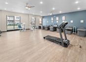 Thumbnail 7 of 8 - A spacious gym with a treadmill, exercise bikes, and other equipment.