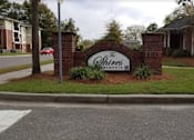 Thumbnail 1 of 16 - The Shires apartments sign is made of brick and has a green bush in front of it.