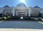 Thumbnail 4 of 6 - A sunny day at a large, multi-story residential building with a driveway in front.