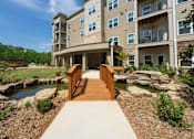 Thumbnail 20 of 38 - A wooden walkway leads to a modern apartment building.