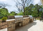 Thumbnail 19 of 38 - A silver grill is on a patio with a brick wall.