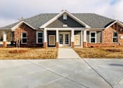 Thumbnail 8 of 8 - A brick house with a grey roof and a concrete driveway.