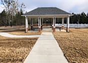 Thumbnail 2 of 8 - A gazebo with a walkway leading to it is surrounded by a grassy area.
