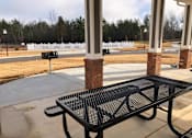 Thumbnail 5 of 8 - A black metal table is in front of a white fence and a brick pillar.