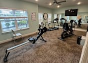Thumbnail 6 of 6 - A spacious home gym with exercise equipment and a television.