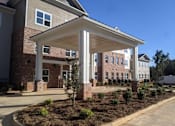 Thumbnail 5 of 6 - A covered walkway leads to a building with a brick facade.