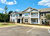 Thumbnail 8 of 8 - A large two-story building with a parking lot in front.