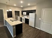 Thumbnail 2 of 6 - A kitchen with a granite countertop and white appliances.