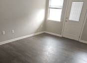 Thumbnail 11 of 14 - A room with a wooden floor and a door on the right side.