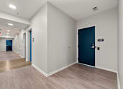 Thumbnail 9 of 13 - A hallway with a blue door and a sign on the wall.