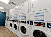 Thumbnail 11 of 13 - A row of white washing machines are lined up in a room.