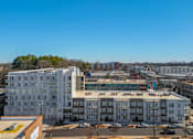 Thumbnail 1 of 13 - A large white building with a red roof is in the foreground of a city street.