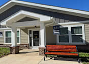 Thumbnail 2 of 9 - A bench is in front of a leasing office.