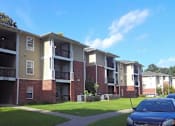 Thumbnail 5 of 16 - A blue car is parked in front of a building with a red brick facade.