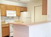 Thumbnail 7 of 16 - A kitchen with white appliances and wooden cabinets.