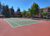 Thumbnail 7 of 18 - a tennis court in front of a building with trees