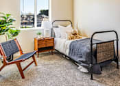 Thumbnail 25 of 53 - A bedroom with a bed, chair, and window.
