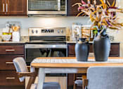 Thumbnail 28 of 53 - A kitchen with a table and chairs and a microwave above the stove.