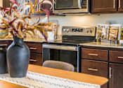 Thumbnail 11 of 53 - A kitchen with brown cabinets and a wooden table.