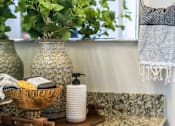 Thumbnail 16 of 53 - A bathroom with a green plant in a vase.