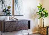 Thumbnail 10 of 53 - A room with a TV stand, two paintings, a plant, and a basket.