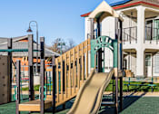 Thumbnail 12 of 53 - A playground with a slide and a building in the background.
