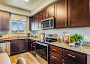 Thumbnail 40 of 53 - A kitchen with dark wood cabinets and granite countertops.