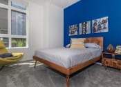 Thumbnail 9 of 24 - a bedroom with a blue accent wall and a bed with a wooden headboard at Napoleon Apartments, Tacoma, WA