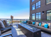 Thumbnail 5 of 24 - an outdoor patio with a firepit and lounge seating with a view of the city at Napoleon Apartments, Tacoma