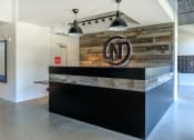 Thumbnail 22 of 24 - a reception desk with a reclaimed wood wall behind it at Napoleon Apartments, Tacoma, WA 98402