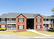 Thumbnail 3 of 14 - A red brick apartment building with a green lawn in front at Ballantyne Commons of Stockbridge Apartments, Stockbridge, Georgia