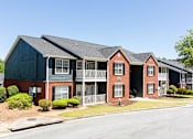 Thumbnail 2 of 14 - A row of townhouses with a clear blue sky above at Ballantyne Commons of Stockbridge Apartments, Georgia