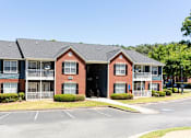 Thumbnail 1 of 14 - A red brick apartment building with a parking lot in front at Ballantyne Commons of Stockbridge Apartments, GA, 30281