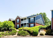 Thumbnail 4 of 14 - A building with a red brick facade and a balcony at Ballantyne Commons of Stockbridge Apartments, Stockbridge, GA, 30281