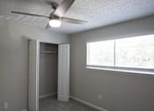 Thumbnail 12 of 20 - A room with a ceiling fan and a window with blinds at The Madison Apartments and Townhomes, Georgia 30044