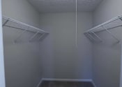 Thumbnail 13 of 20 - Empty walk-in closet with white shelves and a white ceiling at The Madison Apartments and Townhomes, Lawrenceville, GA, 30044