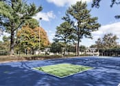 Thumbnail 18 of 20 - A tennis court surrounded by trees and a fence at The Madison Apartments and Townhomes, Georgia
